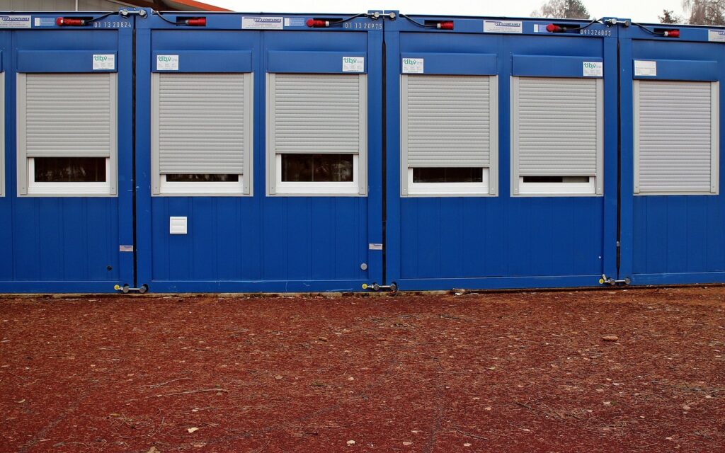 Reihe blauer Wohncontainer als Vergleich zum NAWALO Waldkindergartenwagen