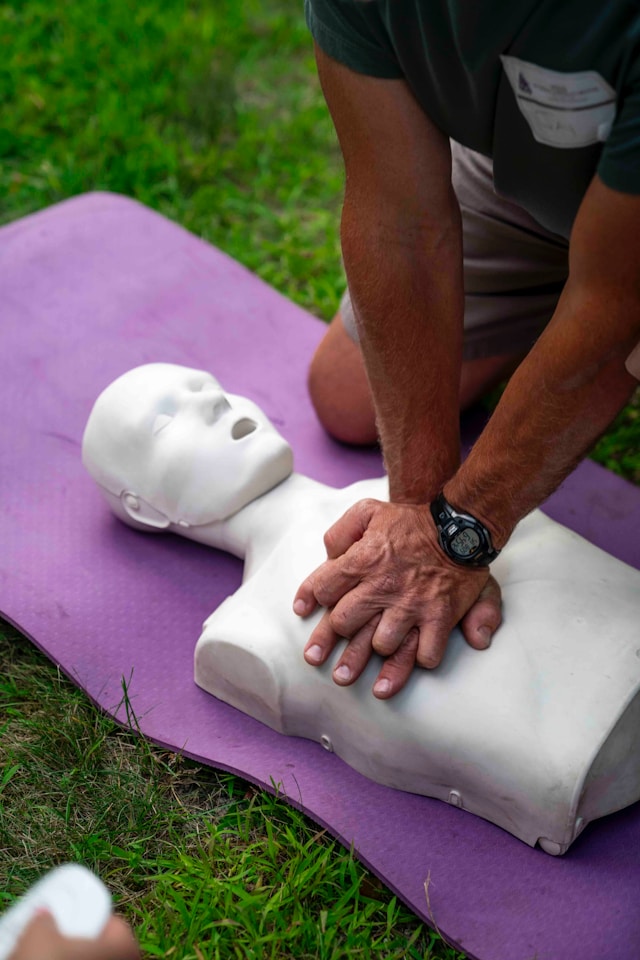 Herzdruckmassage an einer Übungspuppe auf einer Wiese, Symbolbild NAWALO Blog