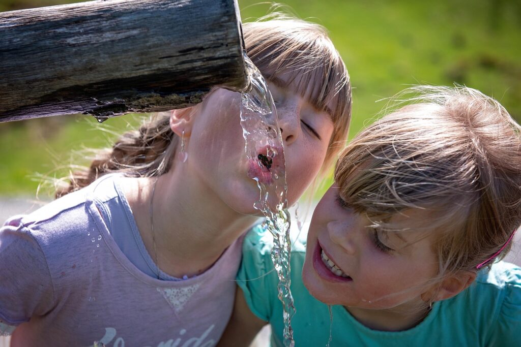 Kinder trinken Wasser aus einem Trinkbrunnen, Symbolbild NAWALO Blog