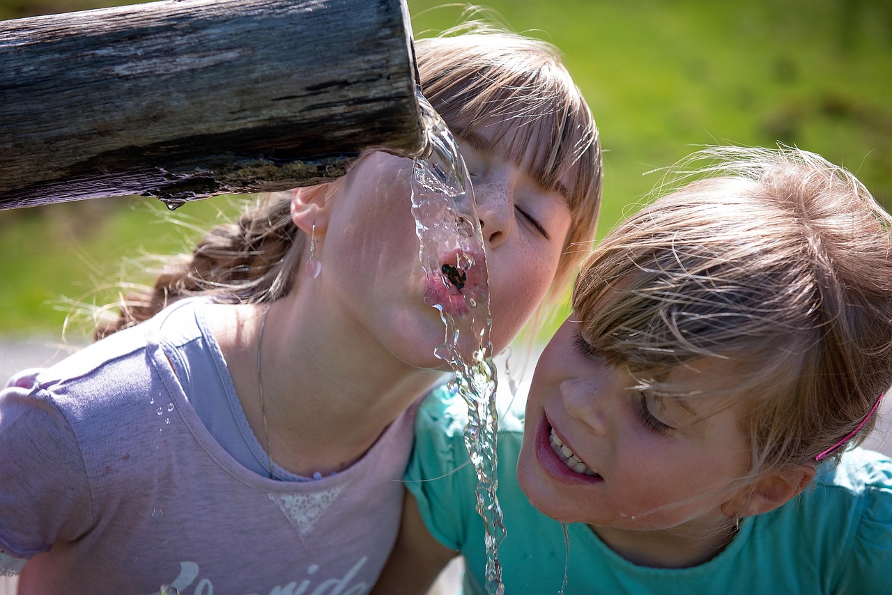 Kinder trinken Wasser aus einem Trinkbrunnen, Symbolbild NAWALO Blog